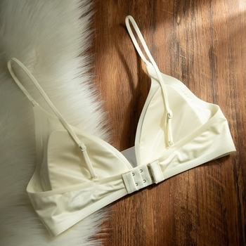 Bevielė trikampio formos liemenėlė iš pieno satino nailono, gilus V formos iškirptė, plonos petnešėlės, be siūlių, plonas formuojamas kaušelis