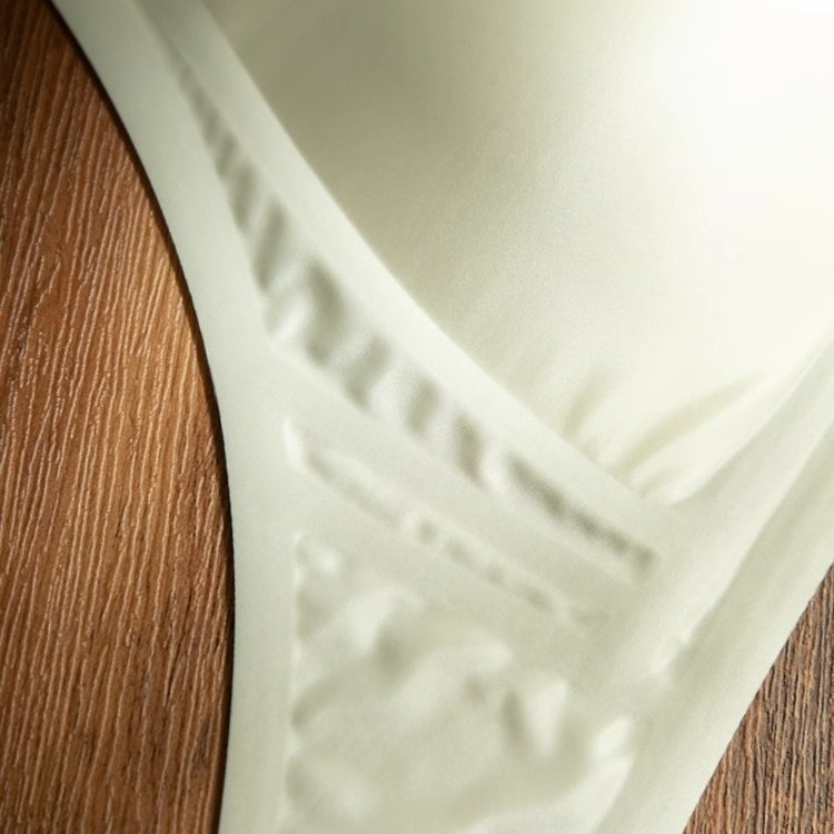 Bevielė trikampio formos liemenėlė iš pieno satino nailono, gilus V formos iškirptė, plonos petnešėlės, be siūlių, plonas formuojamas kaušelis