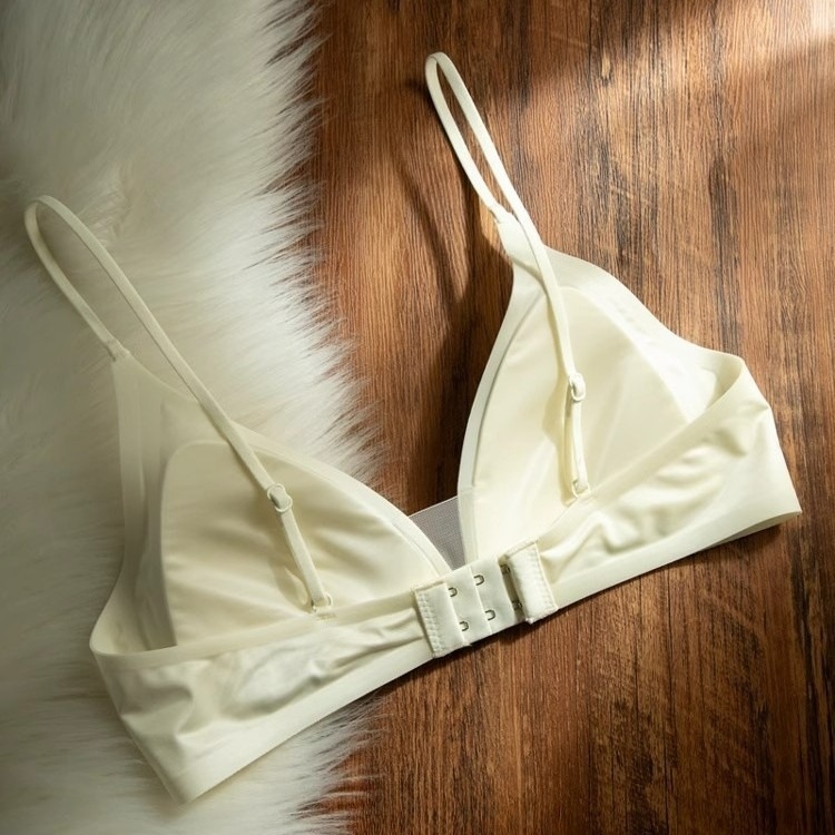 Bevielė trikampio formos liemenėlė iš pieno satino nailono, gilus V formos iškirptė, plonos petnešėlės, be siūlių, plonas formuojamas kaušelis