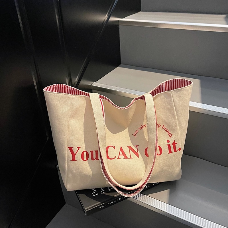 Canvas tote taška v mestskom minimalistickom štýle, horizontálne štvorcový tvar, otvorený vrch, dvojité ramienka, vnútorné vrecká na telefón a ID, podšívka z polyesteru a bavlny, značka Nido, jar 2025