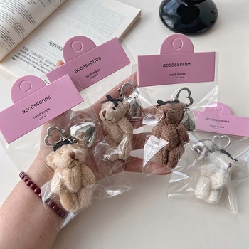 Plüss medve kulcstartó szív alakú medállal – rajzfilmszerű stílus, táskára akasztható dísz; anyag: textil; minta: medve; 2024 nyári kiadás; feldolgozás: félig manuális.