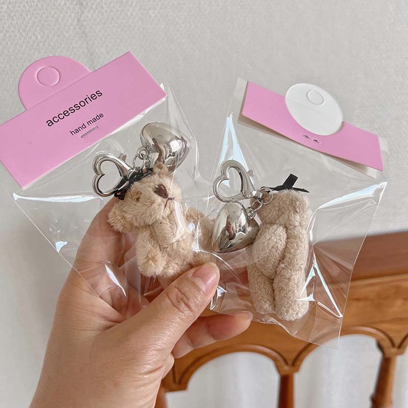 Plüss medve kulcstartó szív alakú medállal – rajzfilmszerű stílus, táskára akasztható dísz; anyag: textil; minta: medve; 2024 nyári kiadás; feldolgozás: félig manuális.