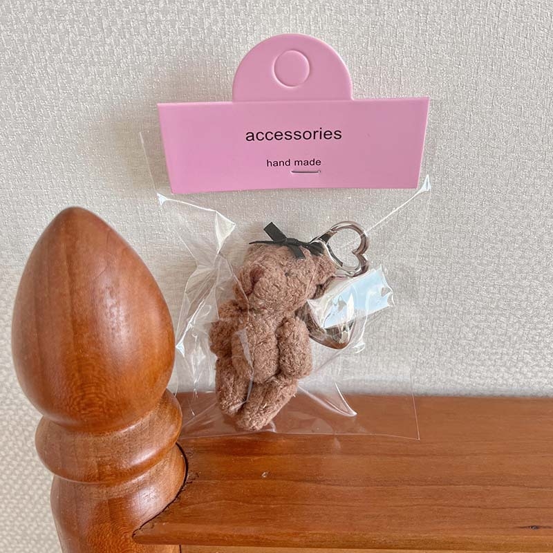 Plüss medve kulcstartó szív alakú medállal – rajzfilmszerű stílus, táskára akasztható dísz; anyag: textil; minta: medve; 2024 nyári kiadás; feldolgozás: félig manuális.