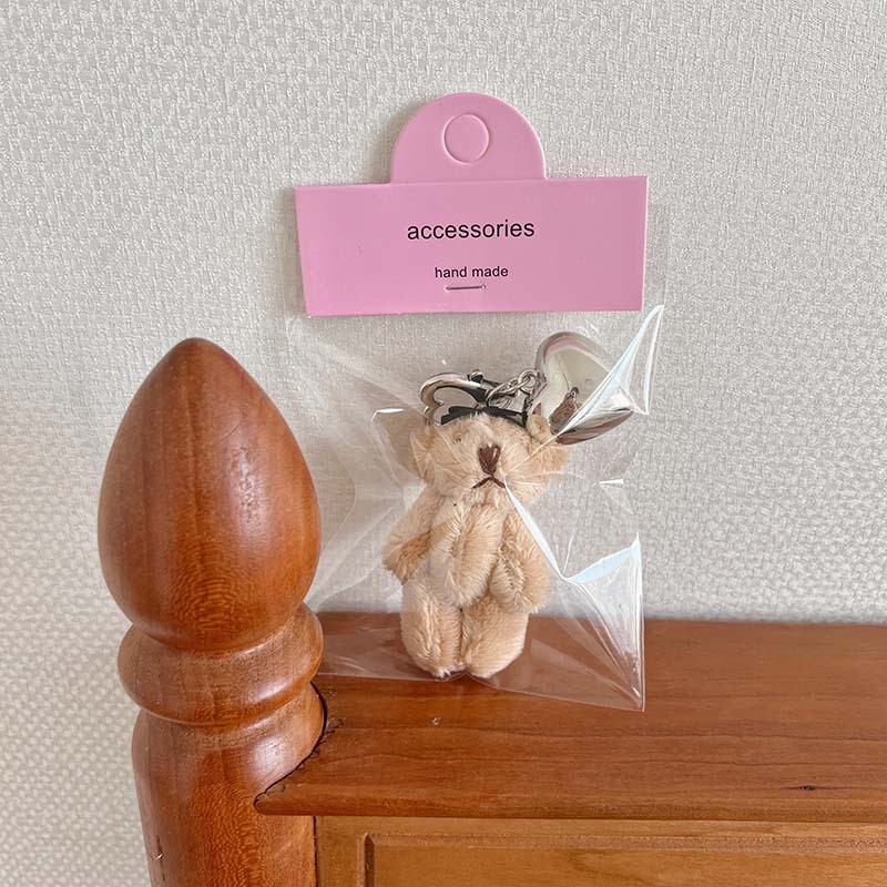 Plüss medve kulcstartó szív alakú medállal – rajzfilmszerű stílus, táskára akasztható dísz; anyag: textil; minta: medve; 2024 nyári kiadás; feldolgozás: félig manuális.