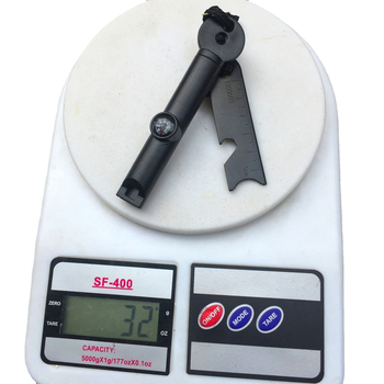 Išorės išlikimo įrankis su paukščių kvietimo švilpuku, kompasu, ugnies uždegimo su kremeniu ir magnio strypu, dantyje atidarytuvas buteliams