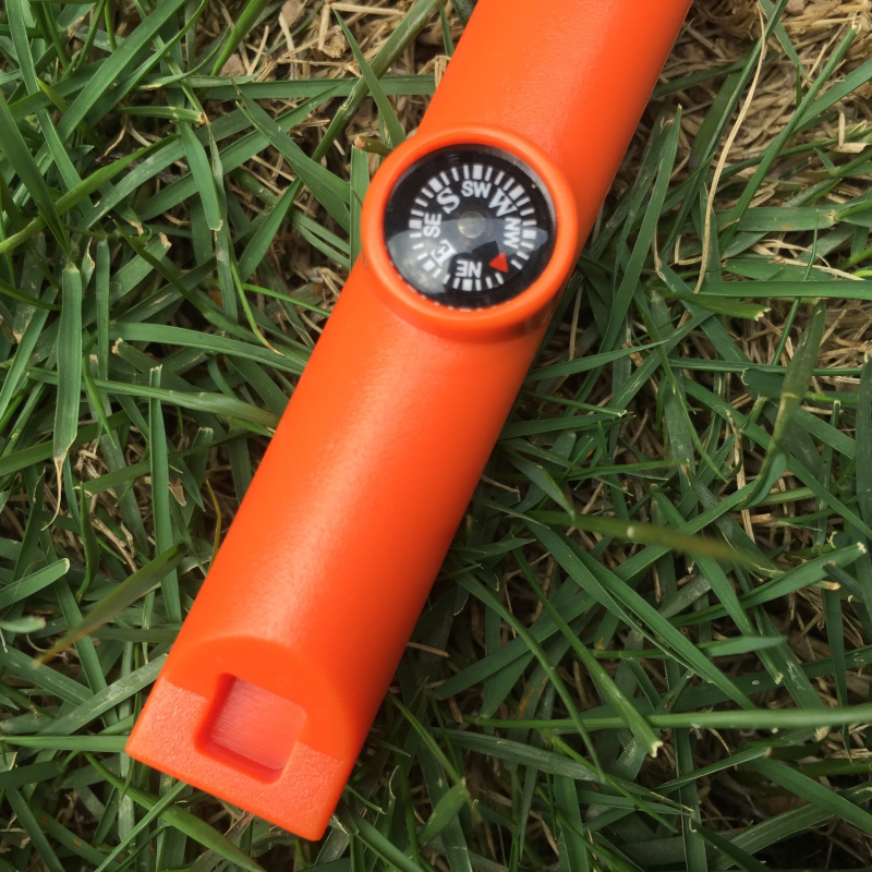 Išorės išlikimo įrankis su paukščių kvietimo švilpuku, kompasu, ugnies uždegimo su kremeniu ir magnio strypu, dantyje atidarytuvas buteliams