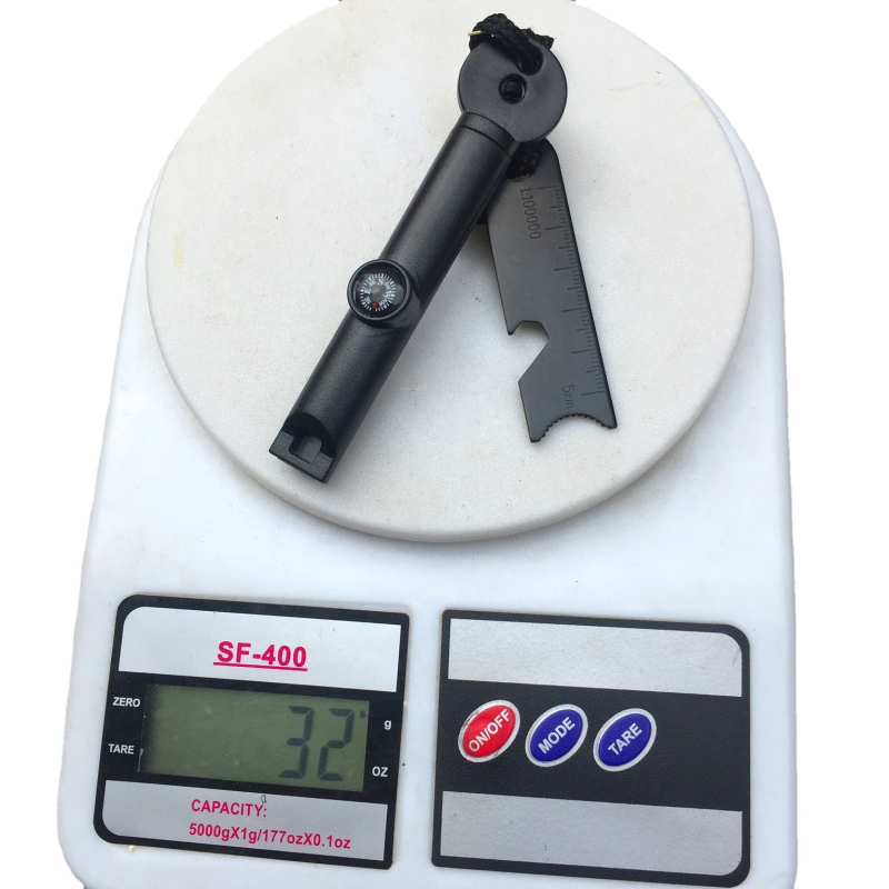 Išorės išlikimo įrankis su paukščių kvietimo švilpuku, kompasu, ugnies uždegimo su kremeniu ir magnio strypu, dantyje atidarytuvas buteliams