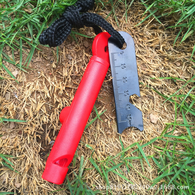 Išorės išlikimo įrankis su paukščių kvietimo švilpuku, kompasu, ugnies uždegimo su kremeniu ir magnio strypu, dantyje atidarytuvas buteliams