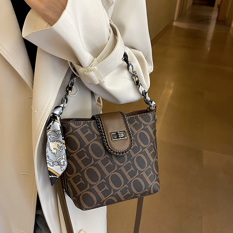 Geantă bucket din PU, formă verticală pătrată, închidere cu fermoar, căptușeală din poliester, o singură curea de umăr.