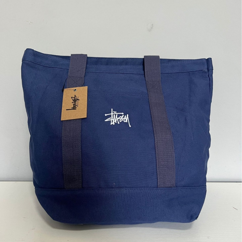 Stussy Canvas Tote Bag – Mestská jednoduchosť, plátený materiál, vodorovný štvorcový tvar, otvorené horné otváranie, vrecko na telefón, dvojité rúčky