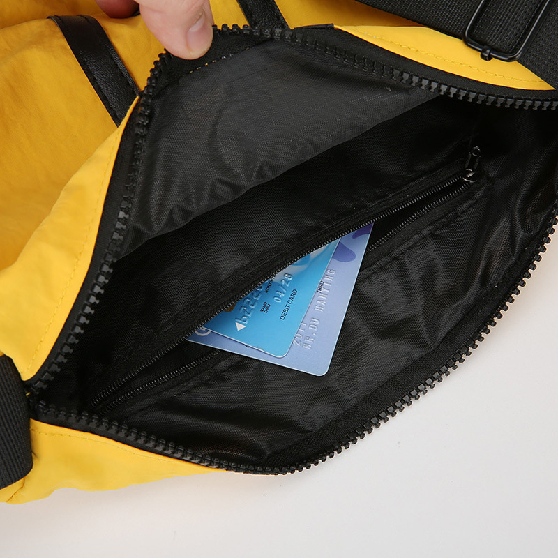 Nylonová taška cez rameno, horizontálny štvorcový tvar, zapínanie na zips, vnútorná kapsa na zips a kapsa na dokumenty, jeden popruh, mestská jednoduchosť.