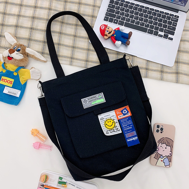 Torba preko ramena od platna, gradski minimalistički stil, uspravni kvadratni oblik, zatvarač, unutarnje pretinice za laptop, karticu/ID, pretinica sa zatvaranjem