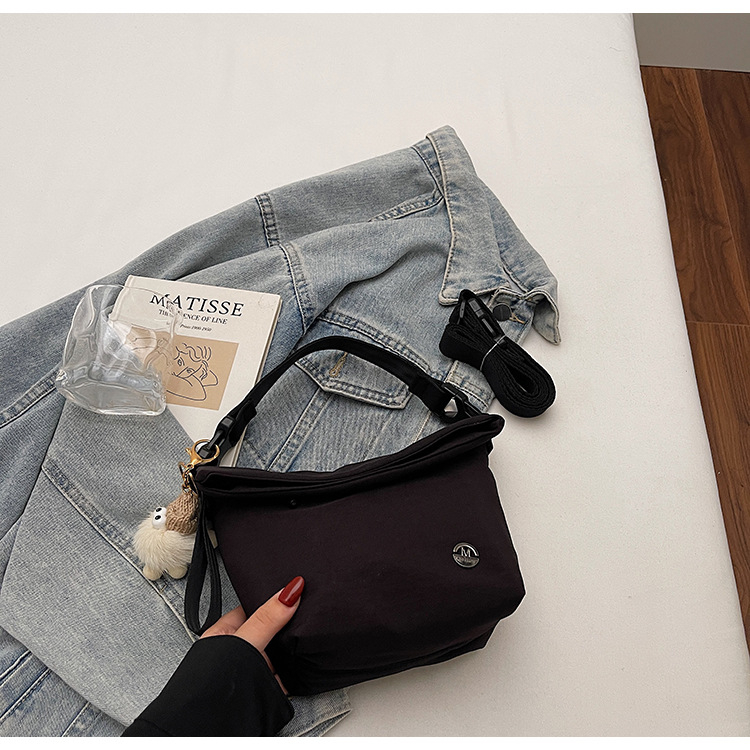Ženska crossbody bucket torbica — gradski minimalistički stil, tekstilni materijal, zatvaranje zipom, poliester podstava, unutarnji džepovi: džep na zatvarač, džep za telefon, džep za dokumente (Jesen 2025)