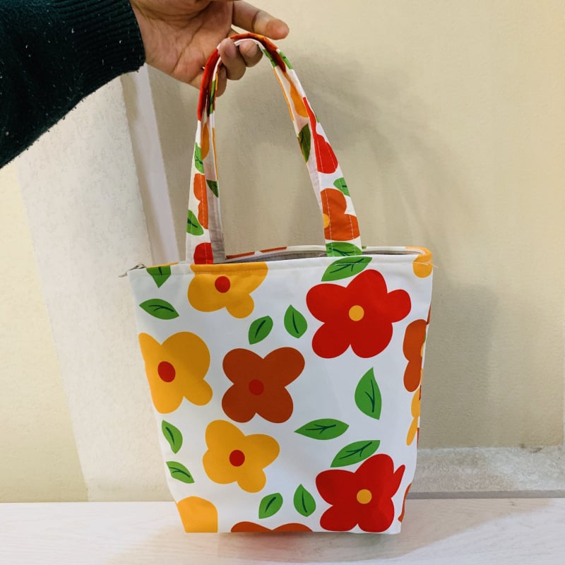 Virágos mintás kézitáska cipzárral, kompozit anyagból, bélés vászon, függőleges négyzetes formájú, belső zsebek telefon és személyazonosító igazolvány számára