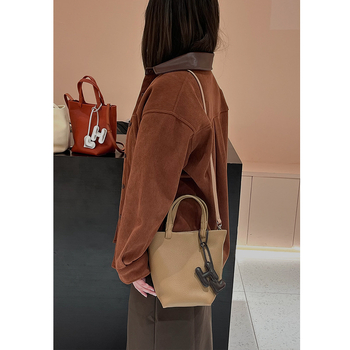 Geantă bucket din piele naturală cu închidere magnetică, textură moale, buzunare interne pentru telefon și card de identificare, design urban minimalist