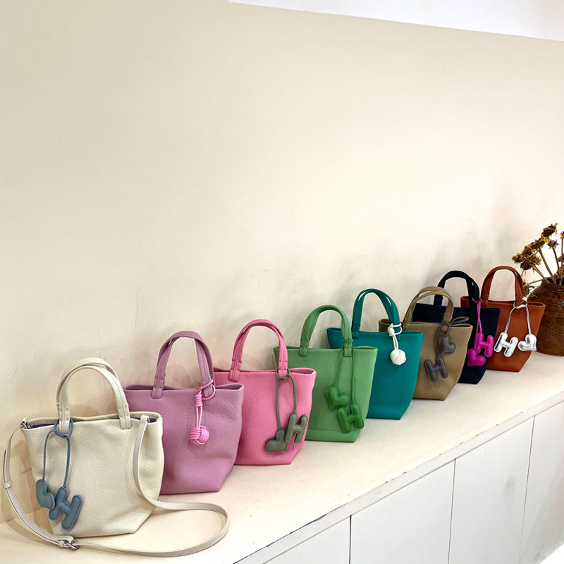 Geantă bucket din piele naturală cu închidere magnetică, textură moale, buzunare interne pentru telefon și card de identificare, design urban minimalist