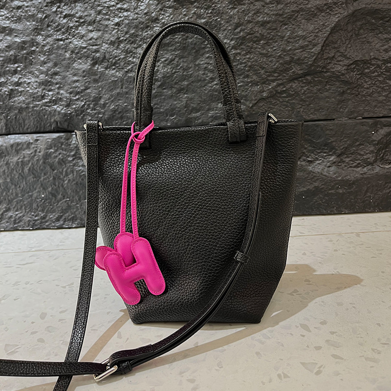 Geantă bucket din piele naturală cu închidere magnetică, textură moale, buzunare interne pentru telefon și card de identificare, design urban minimalist