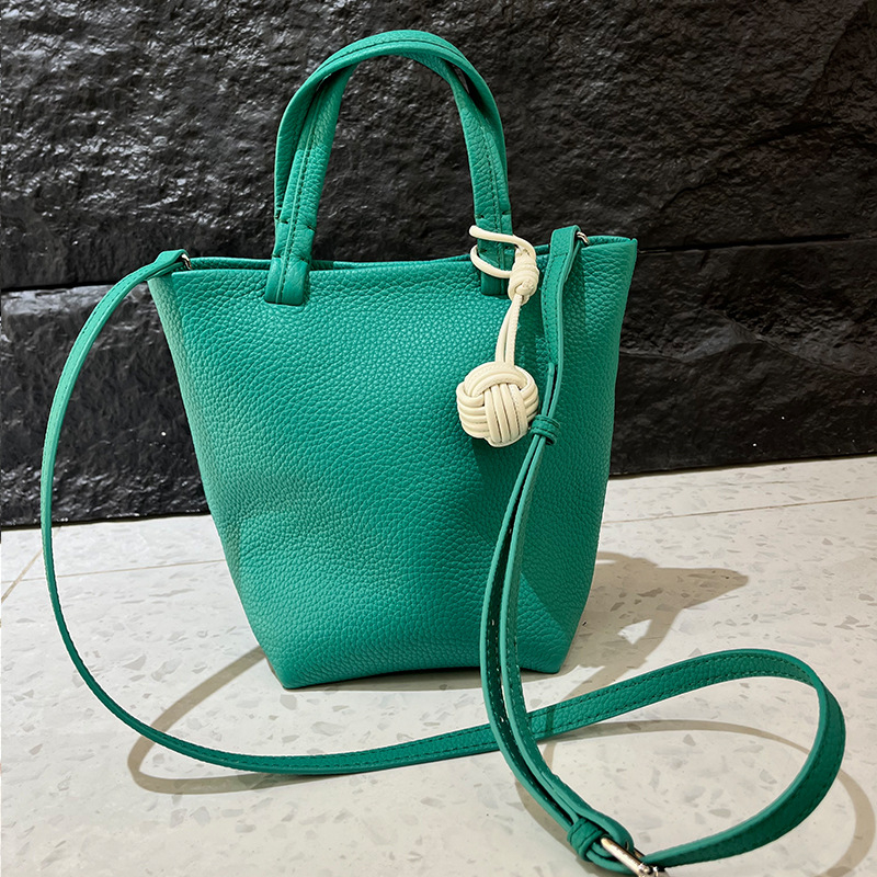 Geantă bucket din piele naturală cu închidere magnetică, textură moale, buzunare interne pentru telefon și card de identificare, design urban minimalist