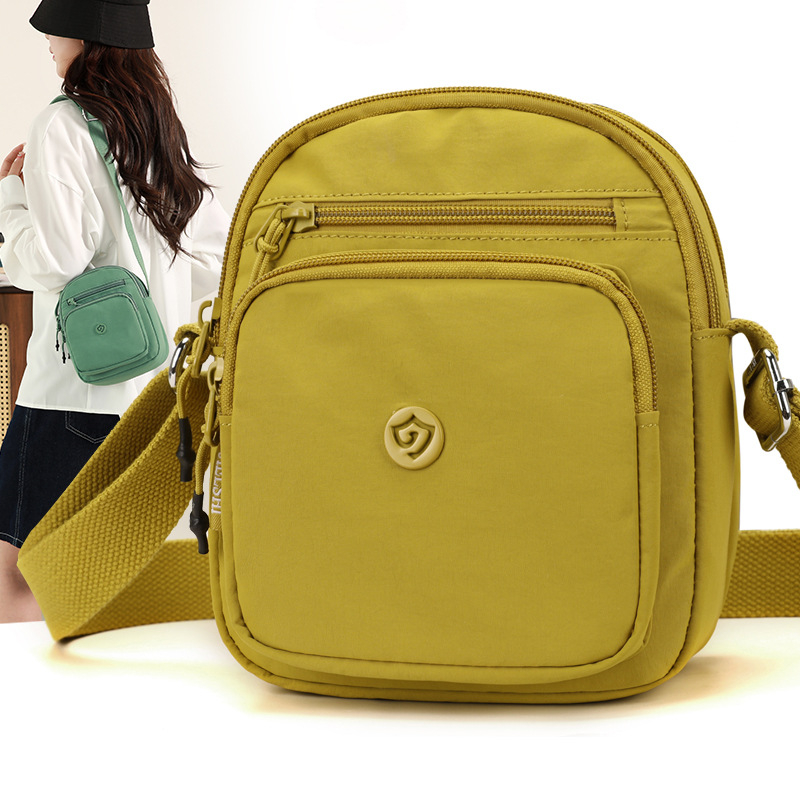 Найлонова кроссбоди чанта с вертикална квадратна форма, цип за затваряне, джоб за мобилен телефон и вътрешен джоб-патч.