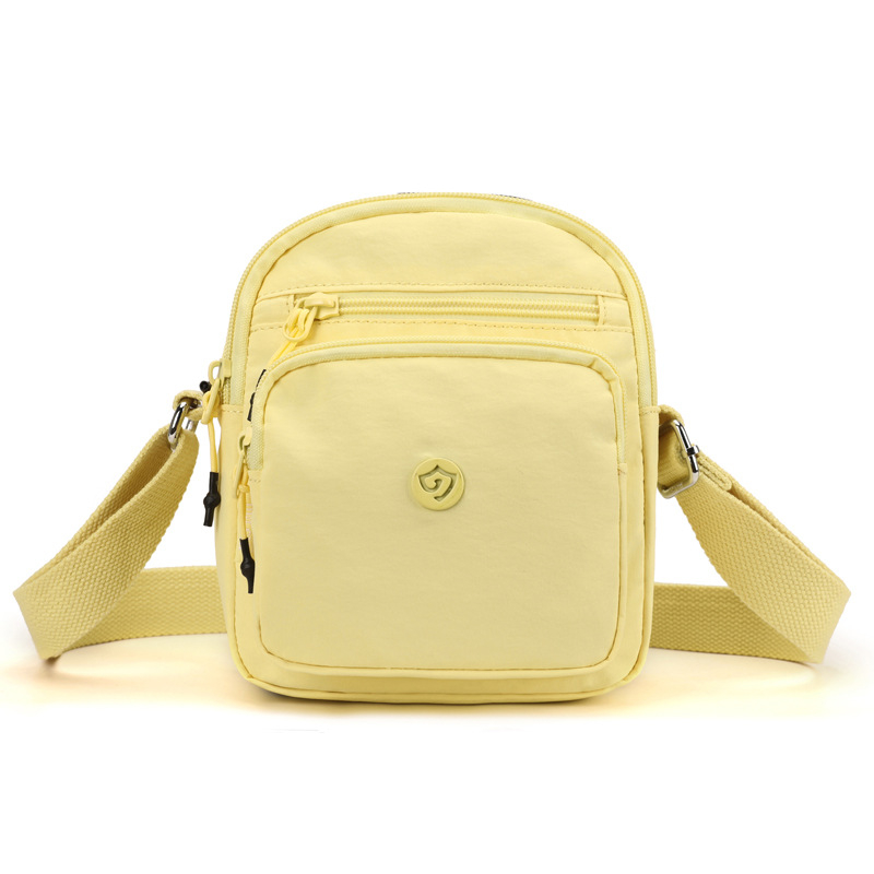 Найлонова кроссбоди чанта с вертикална квадратна форма, цип за затваряне, джоб за мобилен телефон и вътрешен джоб-патч.