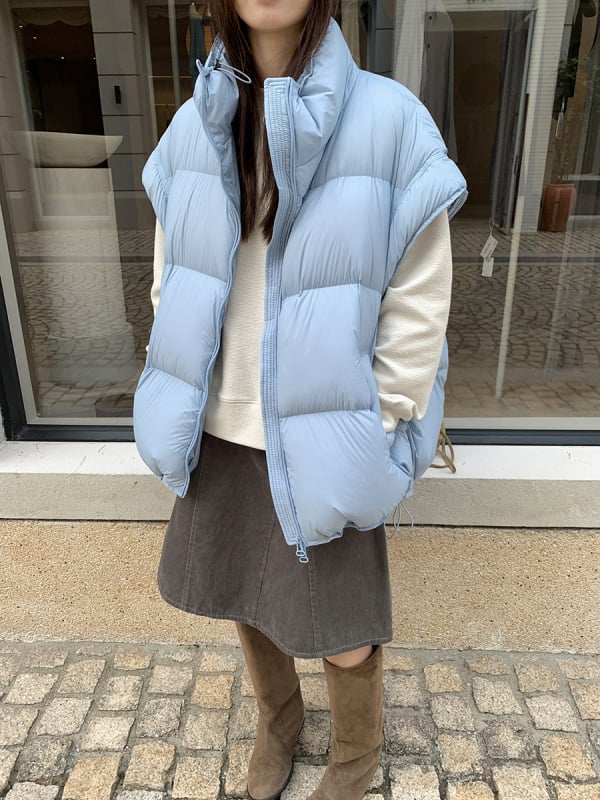 Sieviešu pūka veste ar stāvošu apkakli un rāvējslēdzēju, pūka saturs 86–90%, pildījums: baltais pīļu pūks, galvenais audums: poliesters, brīvs piegriezums, vidēja garuma, ziema 2025