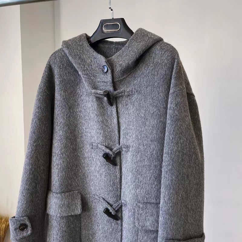 Palton damă din lână cu glugă, lungime 80–100 cm, croială lejeră, închidere cu o singură rând de catarame, 95% lână