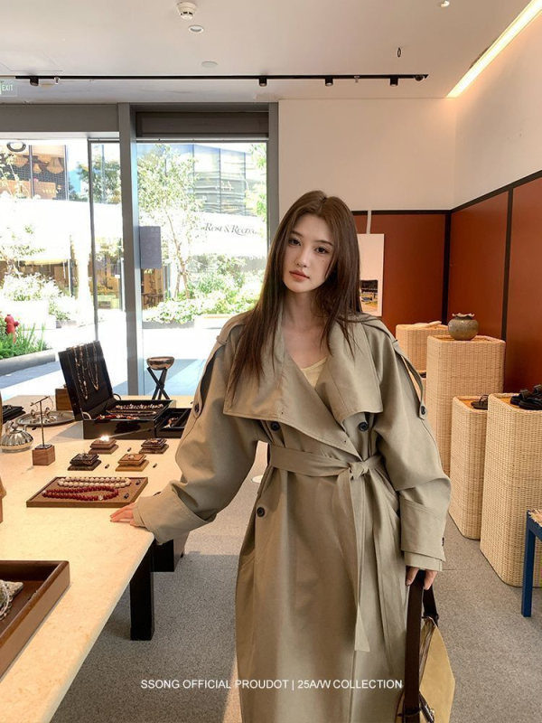 Női övvel és dupla záródású hosszú kabát ferde gallérral és zsebekkel; pamut-poliészter keverék, fő anyag: poliészter, közepes vastagság, 2025 tavasz