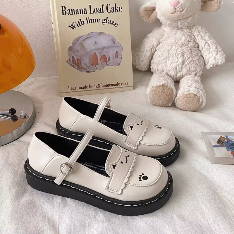 Mary Jane lapos talpú cipő, kerek orr, PU felsőrész, csíkos mintázat, elöl fűzővel és egy csatos pánttal záródó, alacsony sarok, gumírozott talp