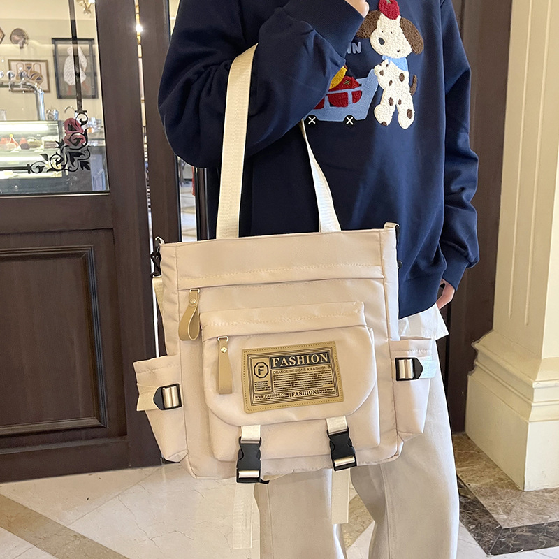 Messenger táska japán stílusú munkaruházat retro dizájnnal, mindennapi használatra; Anyag: Oxford vászon; Bélése: poliészter; Nyitás: cipzár; Forma: horizontális négyzet; Három vállpánt