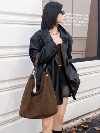 Nubukinės odos kibiro formos delninė pečių su minkšta rankena, matinė apdaila, poliesterio-paminkštintas pamušalas, vidinės kišenės telefonui ir dokumentams, ruduo 2025