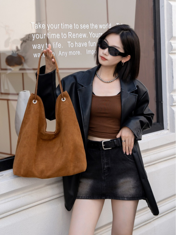 Nubukinės odos kibiro formos delninė pečių su minkšta rankena, matinė apdaila, poliesterio-paminkštintas pamušalas, vidinės kišenės telefonui ir dokumentams, ruduo 2025