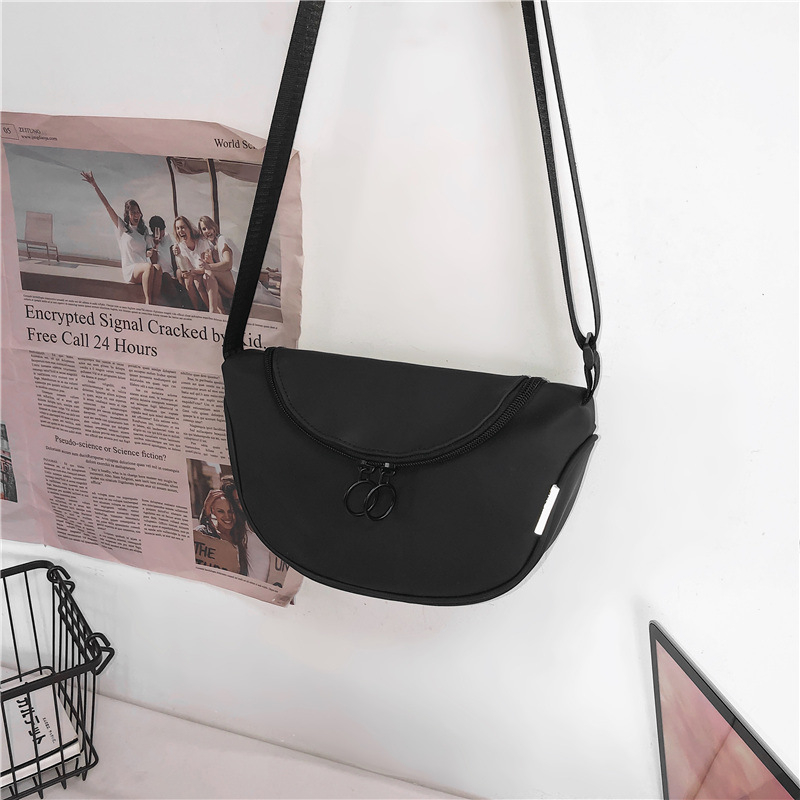 Crossbody torba u gradskoj estetici, laminirana Oxford tkanina, ovalni oblik, zatvaranje zipom, unutarnja pretinica za mobitel i laminirani pretinac sa zipom — izlazi jesen 2025