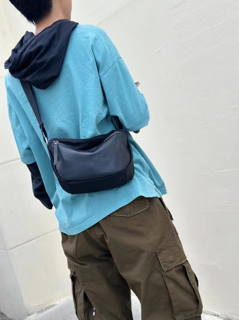Valódi bőrből készült crossbody táska vízálló anyaggal, horizontális négyzet alakú forma, cipzáros zárás, belső zsebek telefonra és személyi igazolványra — utcai divat stílus