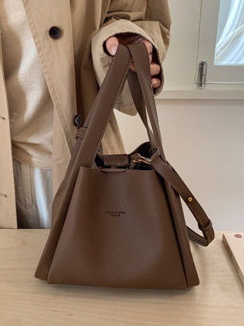 Enzun geantă bucket din piele ecologică — stil retro, lansare toamnă 2025. Formă de găleată, închidere magnetică. Interior: buzunar cu fermoar, buzunar pentru telefon, buzunar pentru documente, buzunar pentru aparat foto. Căptușeală PU. Cu capac. Curea de 