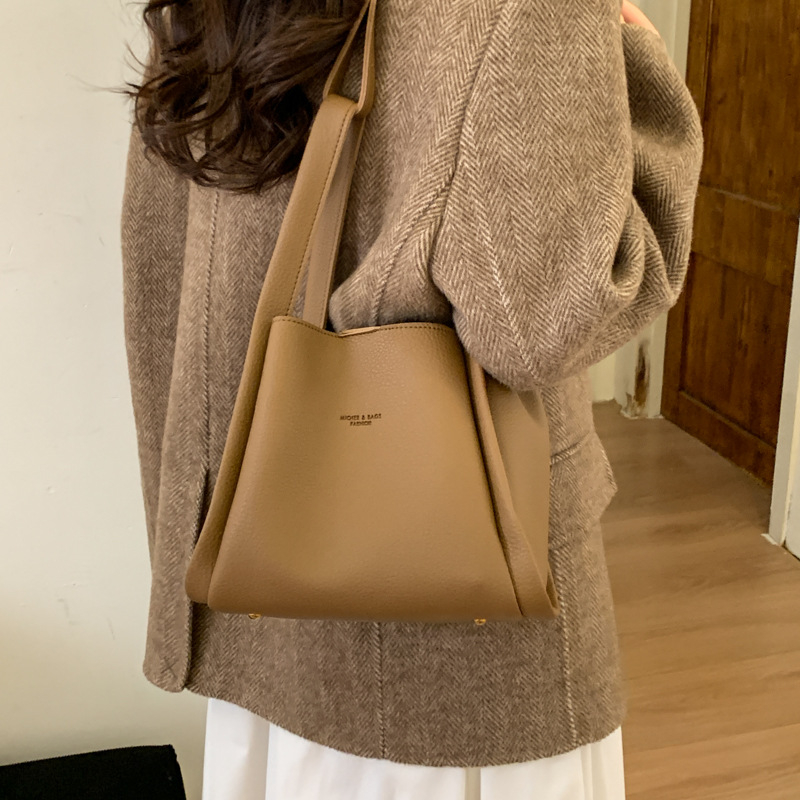 Enzun geantă bucket din piele ecologică — stil retro, lansare toamnă 2025. Formă de găleată, închidere magnetică. Interior: buzunar cu fermoar, buzunar pentru telefon, buzunar pentru documente, buzunar pentru aparat foto. Căptușeală PU. Cu capac. Curea de 