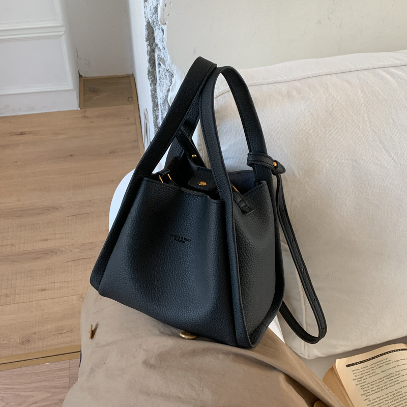 Enzun geantă bucket din piele ecologică — stil retro, lansare toamnă 2025. Formă de găleată, închidere magnetică. Interior: buzunar cu fermoar, buzunar pentru telefon, buzunar pentru documente, buzunar pentru aparat foto. Căptușeală PU. Cu capac. Curea de 