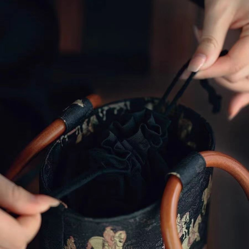 Svilena bucket torba cilindričnog oblika, zatvara se šnuralom i ima unutarnji džep sa zatvaračem