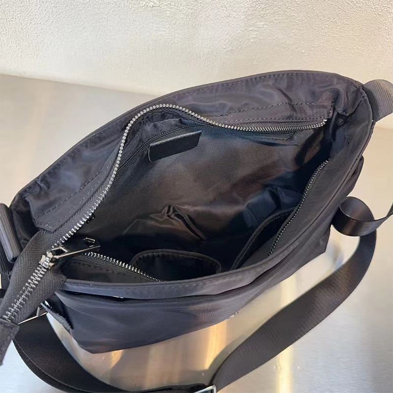 Nylon keresztpántos válltáska, kis négyszögletes formájú, üzleti ingázáshoz; fedeles lezárás; belső zsebek: cipzáras zseb és telefonzseb; belső bélés: poliészter-pamut; egy vállpánt