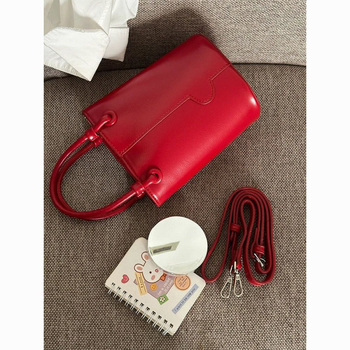 Crvena bucket torba s remenom za nošenje preko tijela i ručnim držalom, elegantna i svestrana