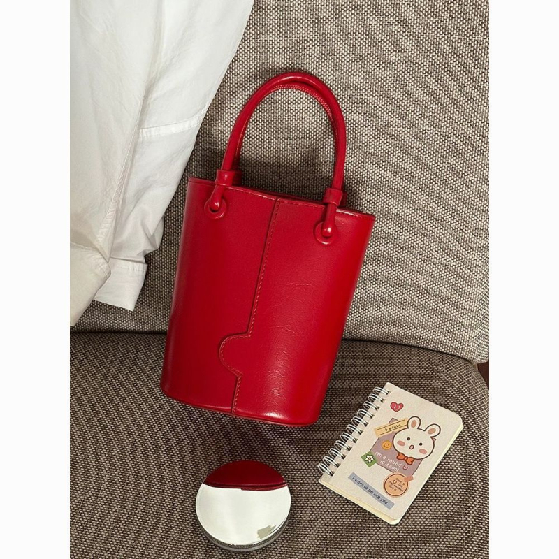 Crvena bucket torba s remenom za nošenje preko tijela i ručnim držalom, elegantna i svestrana
