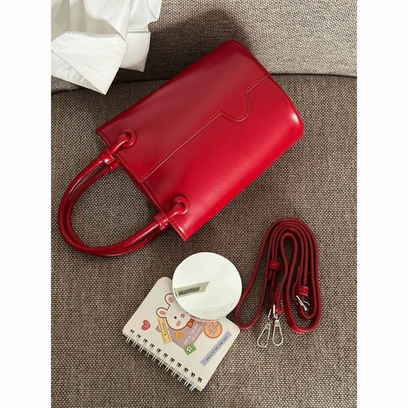 Crvena bucket torba s remenom za nošenje preko tijela i ručnim držalom, elegantna i svestrana
