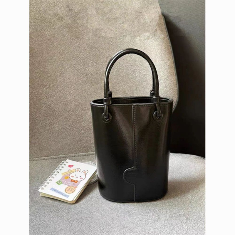 Crvena bucket torba s remenom za nošenje preko tijela i ručnim držalom, elegantna i svestrana