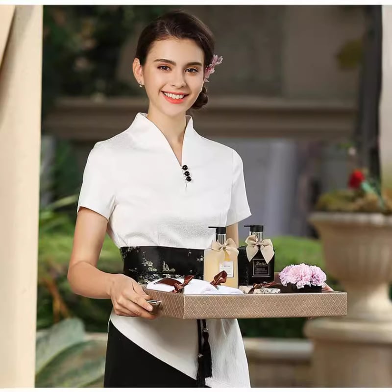 Uniformă pentru salon de înfrumusețare: costum cu pantaloni croiți în talie largă, decolteu în V, mâneci scurte; material din amestec de bumbac (50–70% bumbac, 15% Cupro); țesătură: bumbac; mâneci: scurte; decolteu: V.