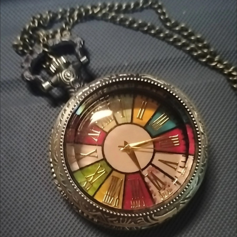 Kabatas pulkstenis ar caurspīdīgu stikla vāciņu, romiešu cipari, kvarca mehānisms Pearl, pasaules laiks, sakausējuma korpuss, apaļš dialis