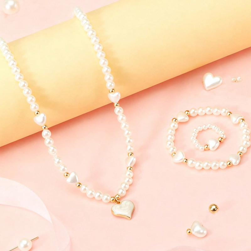 Vaikų perlinių papuošalų rinkinys su širdies formos pakabuku: karoliai, apyrankė ir žiedas (Medžiaga: plastikas/rišalas; Grandinė: perlų eilė; Pakabuko medžiaga: lydinys; Rankų darbo; Amžiaus diapazonas: 3–6, 6–10 ir vyresni nei 10 metų)