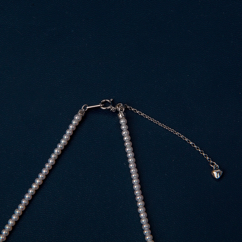 Édesvízi gyöngyökből készült nyaklánc, szinte kör alakú gyöngyök, 925-ös ezüst, rizs alakú gyöngyök díszítéssel, irodai minimalizmus stílus.