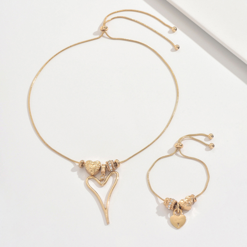 Szív alakú medállal ellátott nyaklánc és karkötő vékony kígyóláncon, ötvözetből; medál anyaga cinkötvözet.