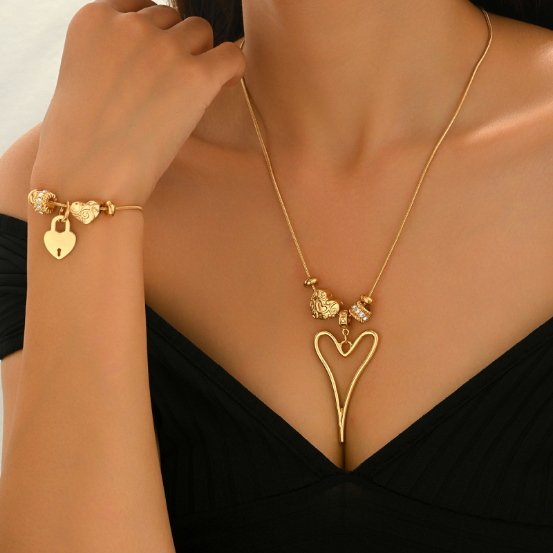 Szív alakú medállal ellátott nyaklánc és karkötő vékony kígyóláncon, ötvözetből; medál anyaga cinkötvözet.