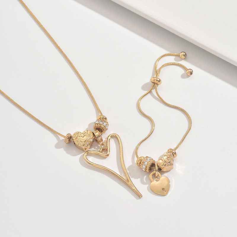 Szív alakú medállal ellátott nyaklánc és karkötő vékony kígyóláncon, ötvözetből; medál anyaga cinkötvözet.
