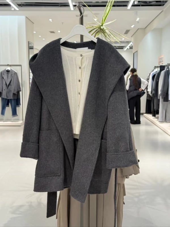 Ženski vuneni kaput s kapuljačom, slobodan kroj, sadržaj vune 50–70%, duljina 50–65 cm, zatvaranje šnalama, elegantan gradski stil, zima 2025